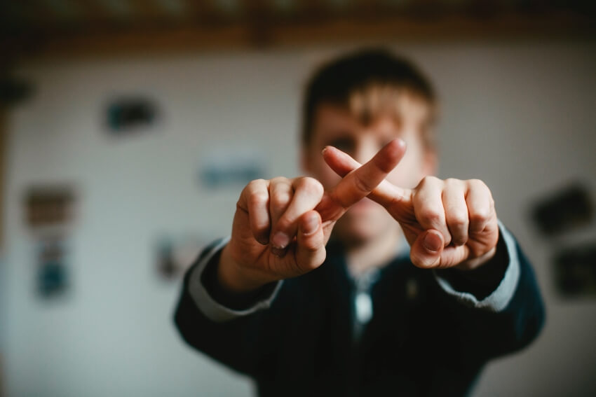 Young Boy Showing X Sign With Fingers