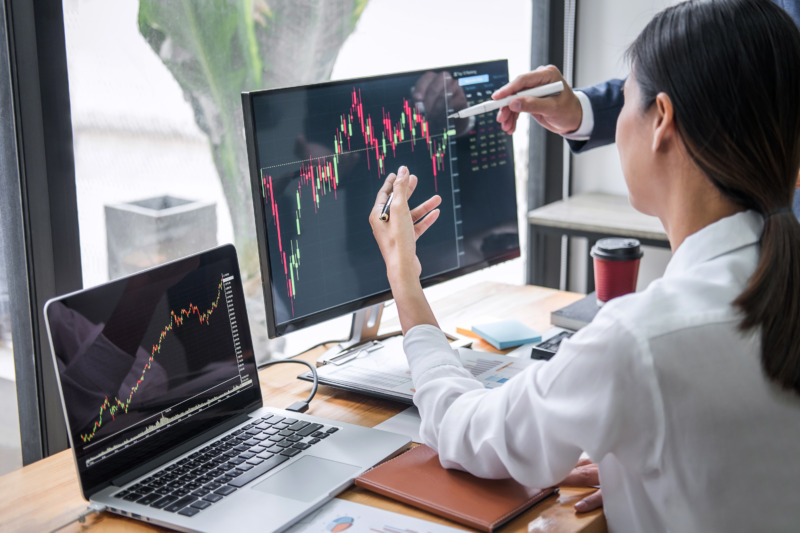 Close-up of a laptop and computer screens showing the financial stock trade stock market graph