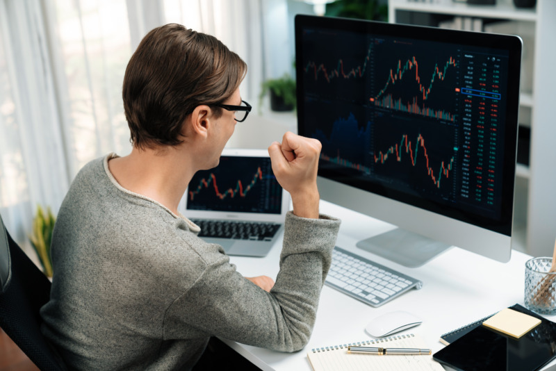 Optimistic trader observes a stock market graph shown on a computer monitor