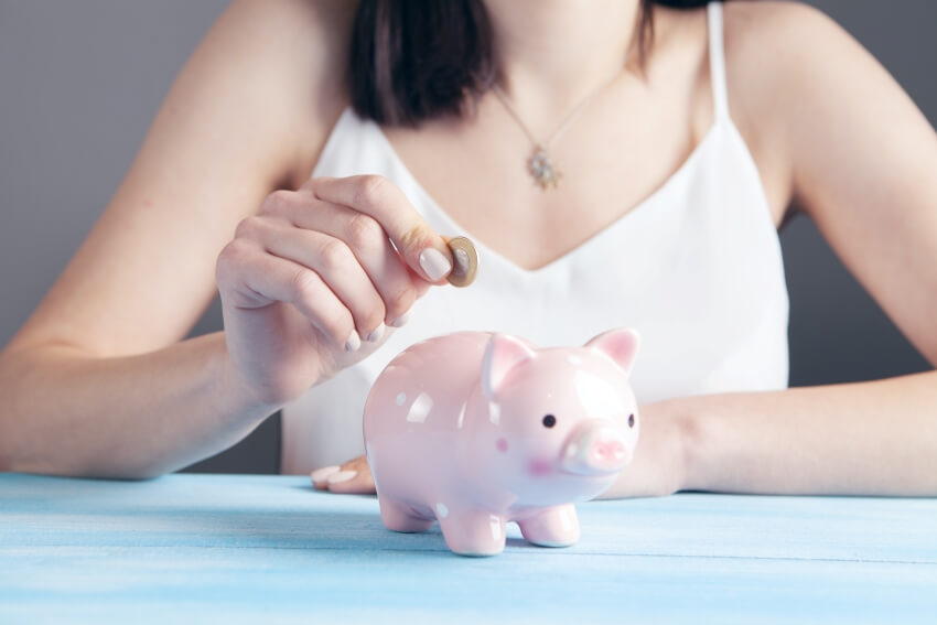 Woman Putting Coin on a Piggy Bank