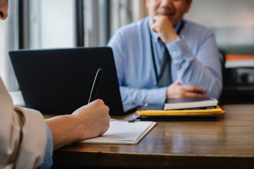 Man Watching a Man Signing Up Papers