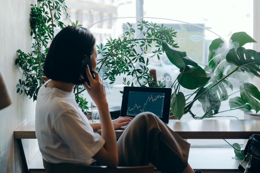 Woman on Phone Checking on Stock Market Display