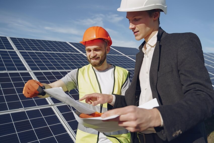 Men Reading Project Plan Beside a Solar Panel