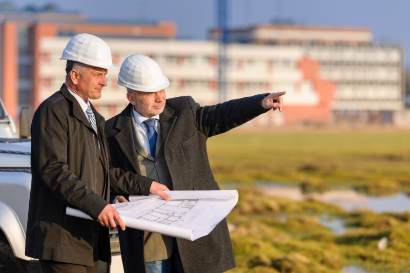 Two senior developers reviewing the plans at a construction site