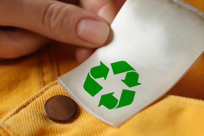 Woman showing clothing label with recycling symbol