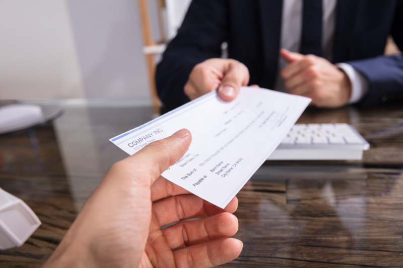 Man in suit handing a cheque for payroll