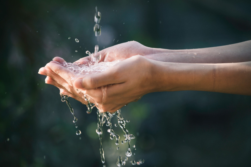 Closeup water flow to hand of women for nature concept on the garden background