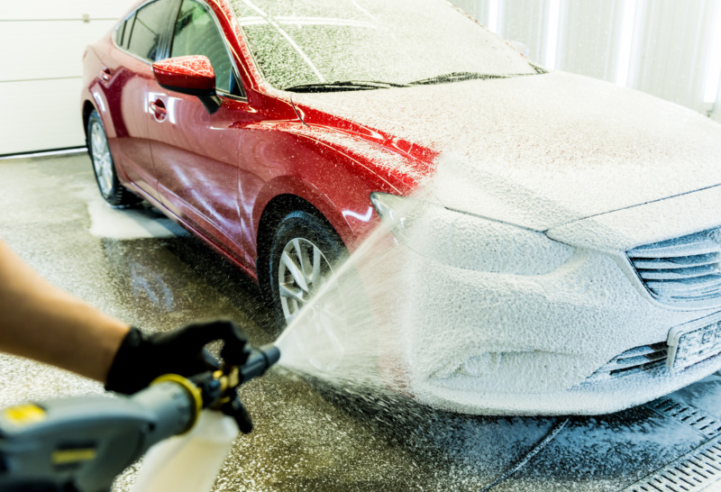 Worker washing a car with foamy soap