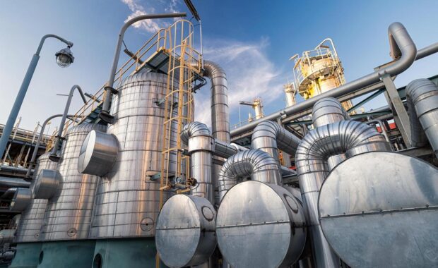 Industrial dehydration system with stainless steel tanks and pipes against a blue sky.