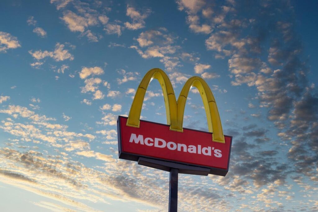 McDonald's golden arches sign against blue sky with scattered clouds at dusk.