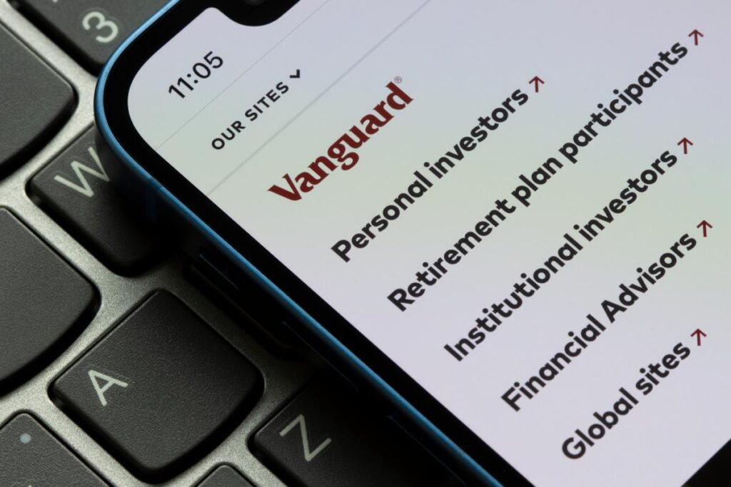 Smartphone with Vanguard investment app on screen over computer keyboard